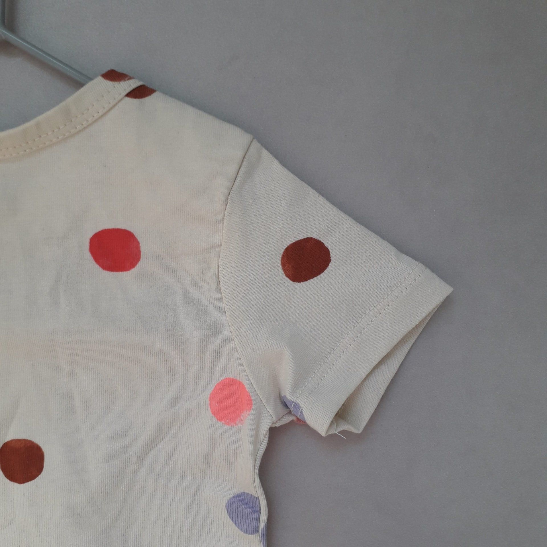 Een wit T-shirt met stippen hangt aan een hanger.