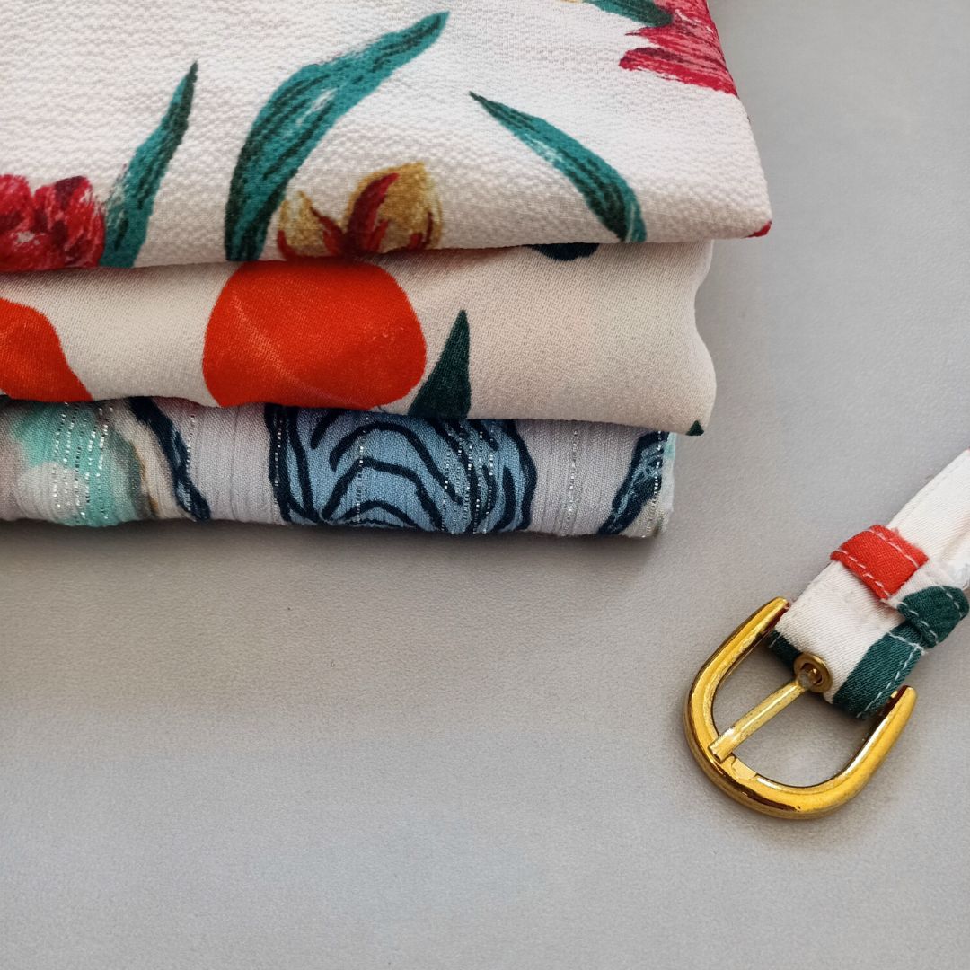 Een stapel stoffen met bloemen erop naast een riem