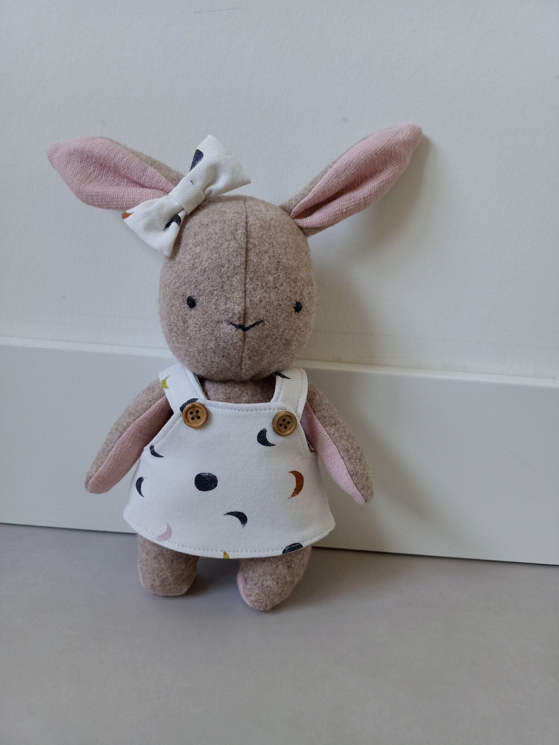 Een herinnerinshaasje gekleed in een overall en met een strik, zit op een tafel.