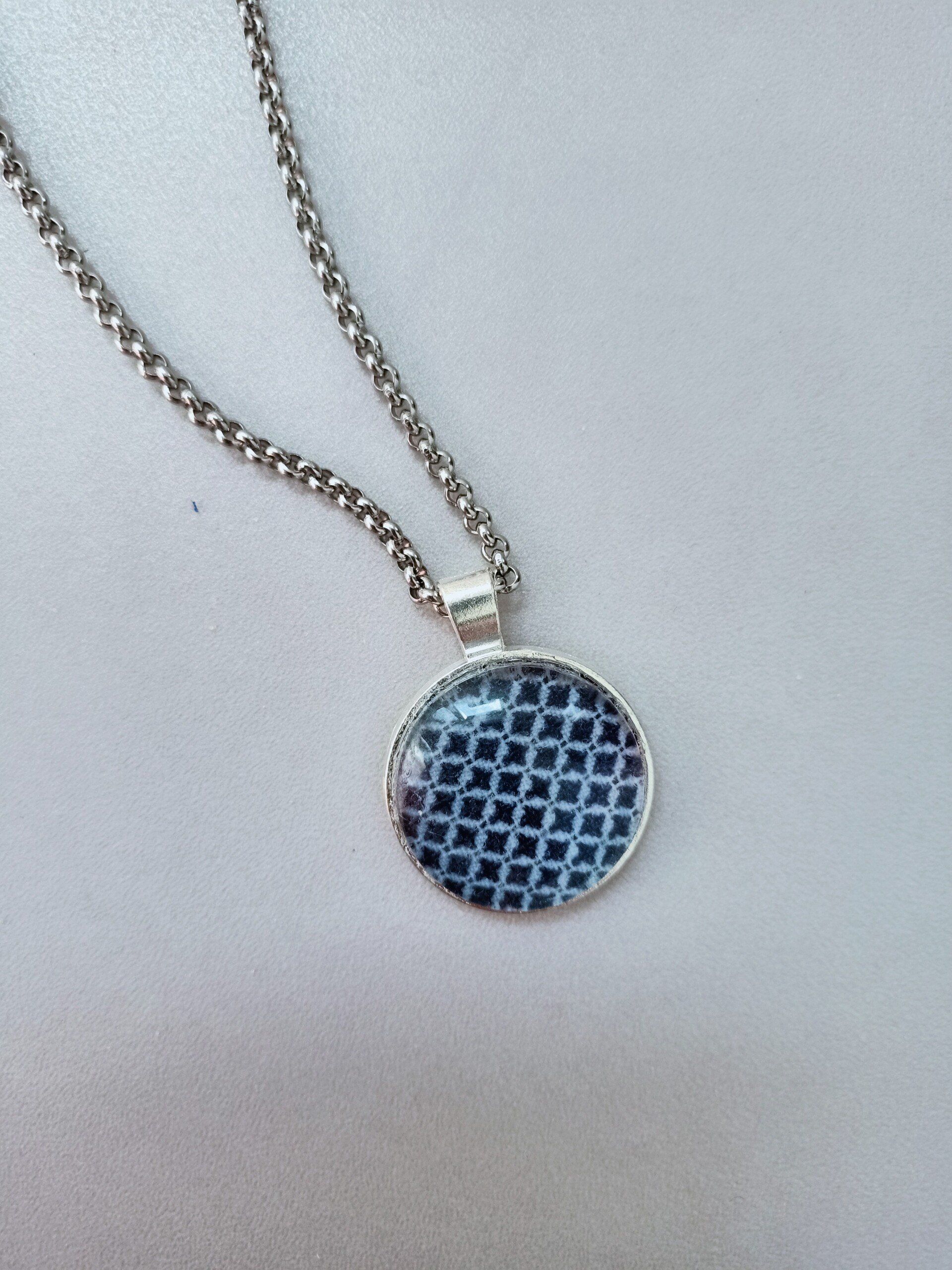 Een zilveren ketting met een blauwe hanger eraan