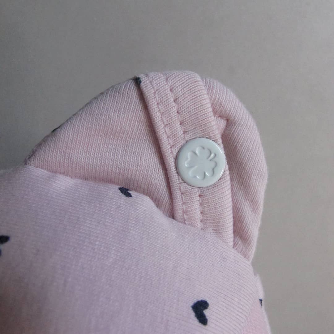 Een close-up van een roze oortje van een herinneringsbeer met een knoop erop.