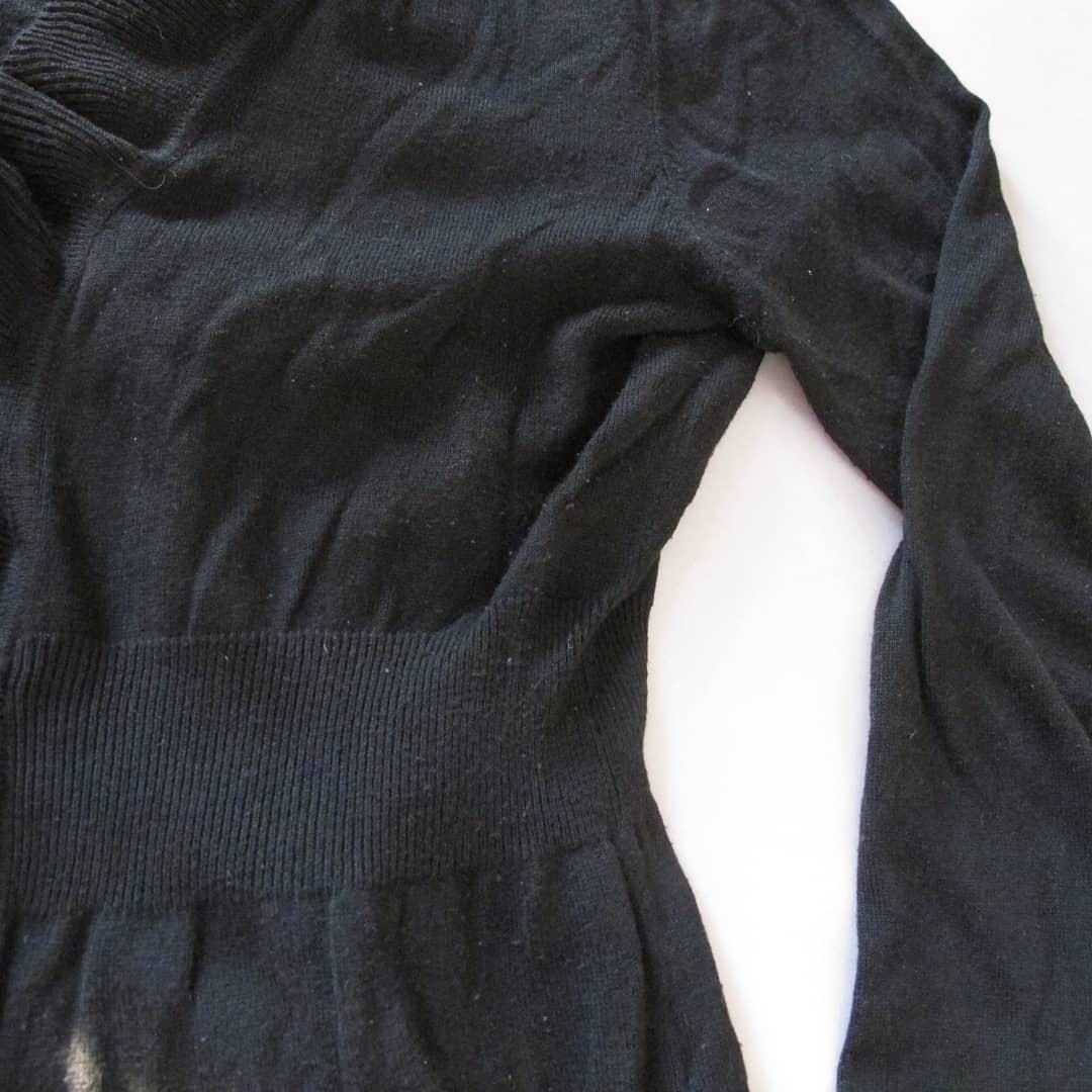 Een zwarte trui met lange mouwen ligt op een wit oppervlak