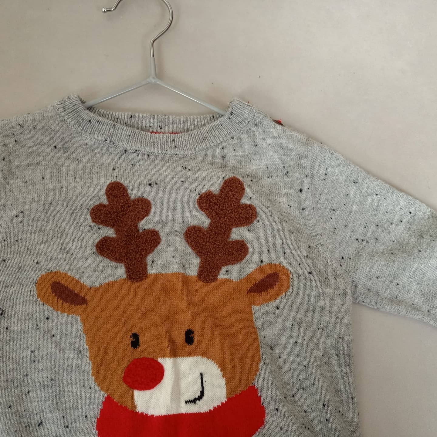 Een trui met een rendier erop hangt aan een hanger