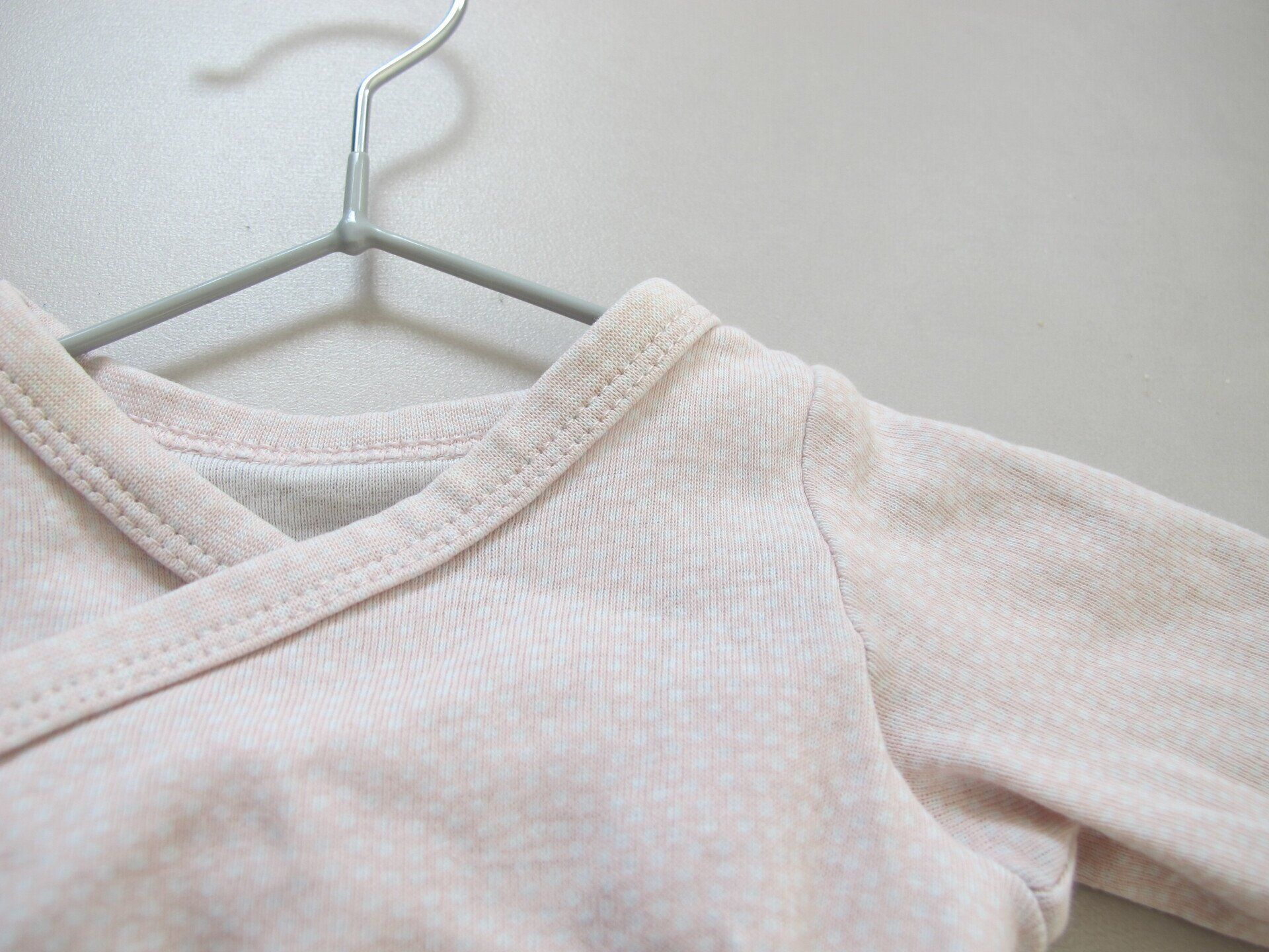 Een close-up van een roze shirt dat aan een hanger hangt.