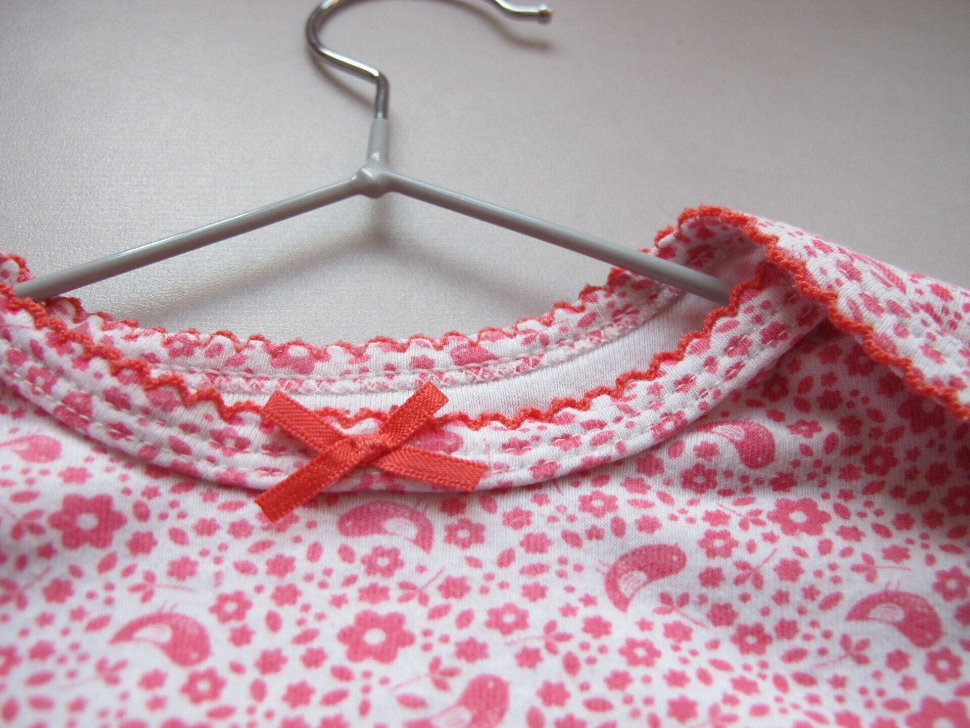 Een close-up van een roze en wit bloemenshirt op een hanger