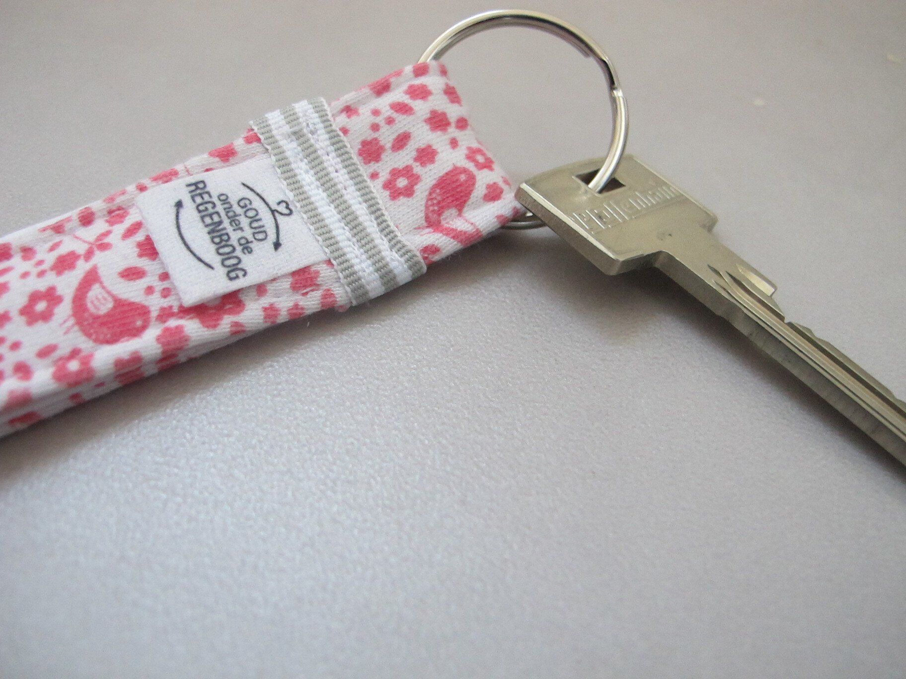Een sleutel aan een sleutelhanger met een roze en wit bloemenpatroon