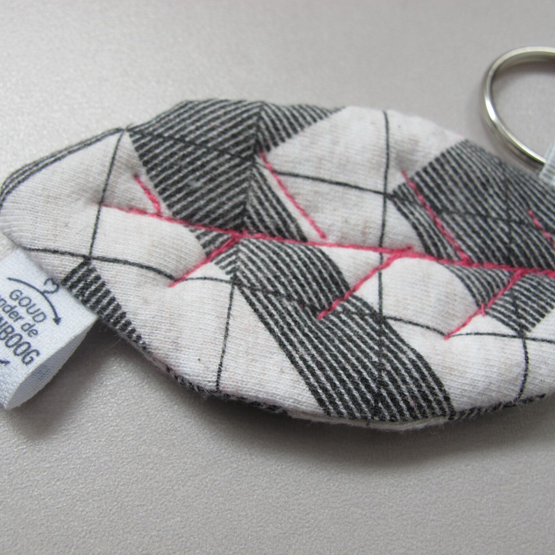 Een zwart-wit geruite sleutelhanger met een label waarop staat 'solid cotton'