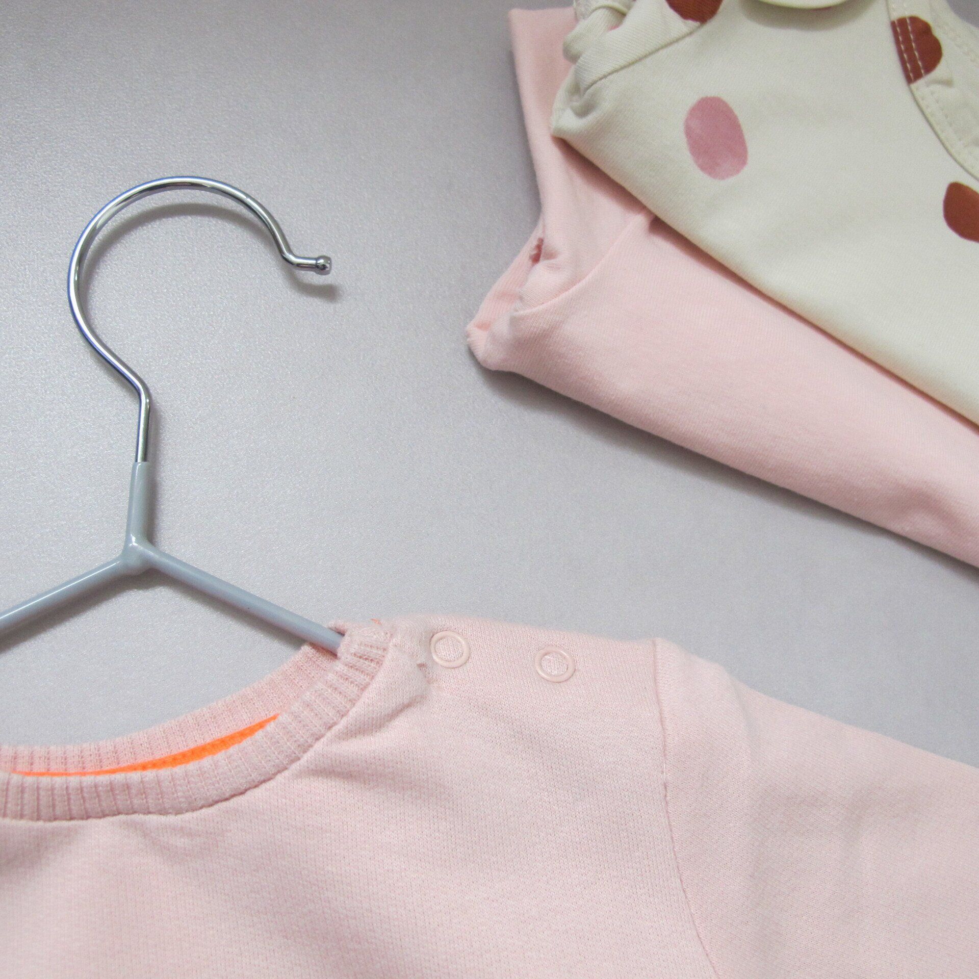 Een roze shirt hangt aan een hanger naast een wit shirt