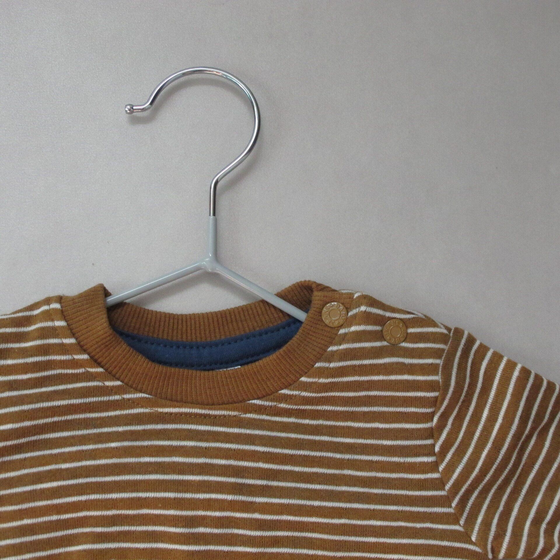 Een bruin-wit gestreept shirt hangt aan een hanger