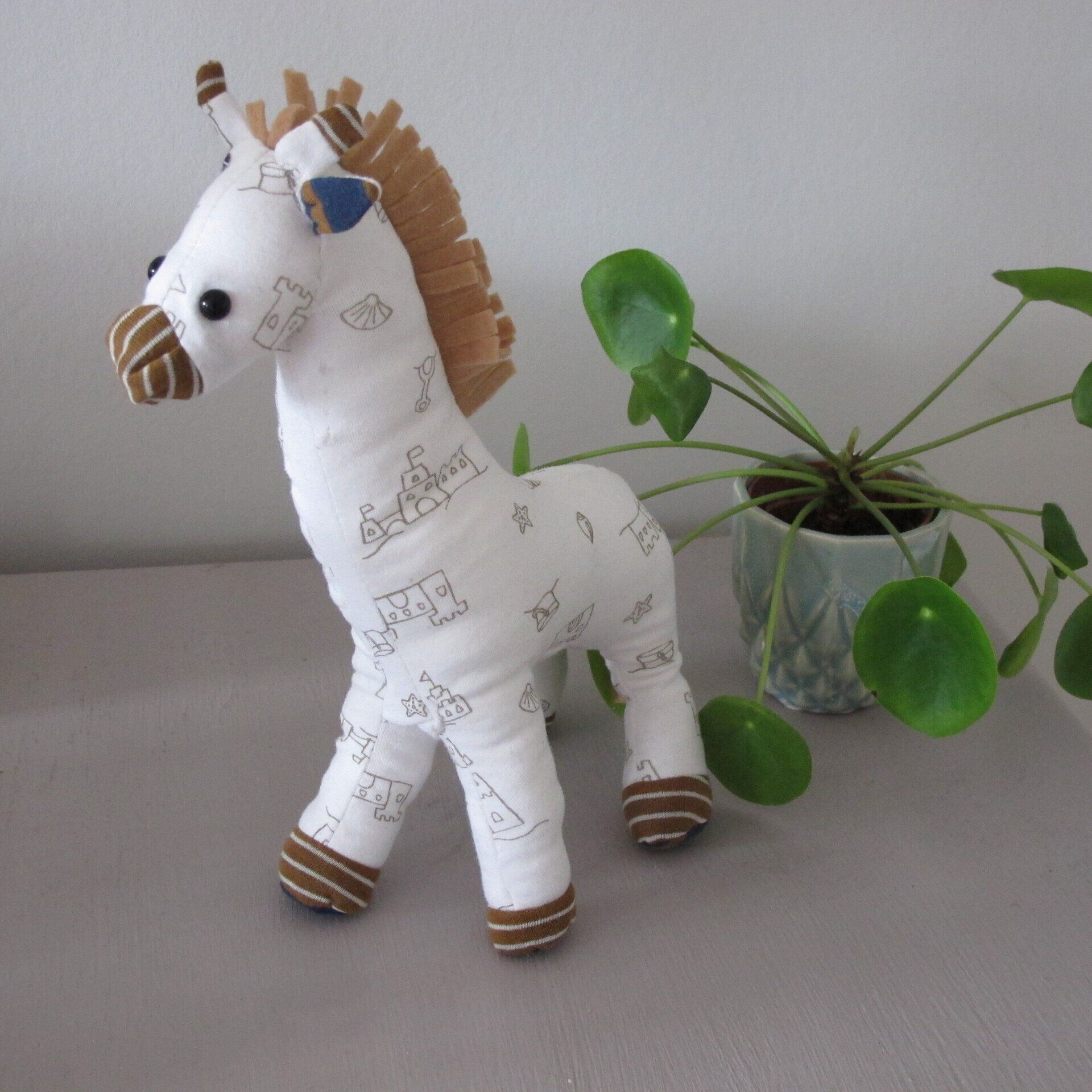 Een opgezet paard met een bruine manen staat naast een potplant