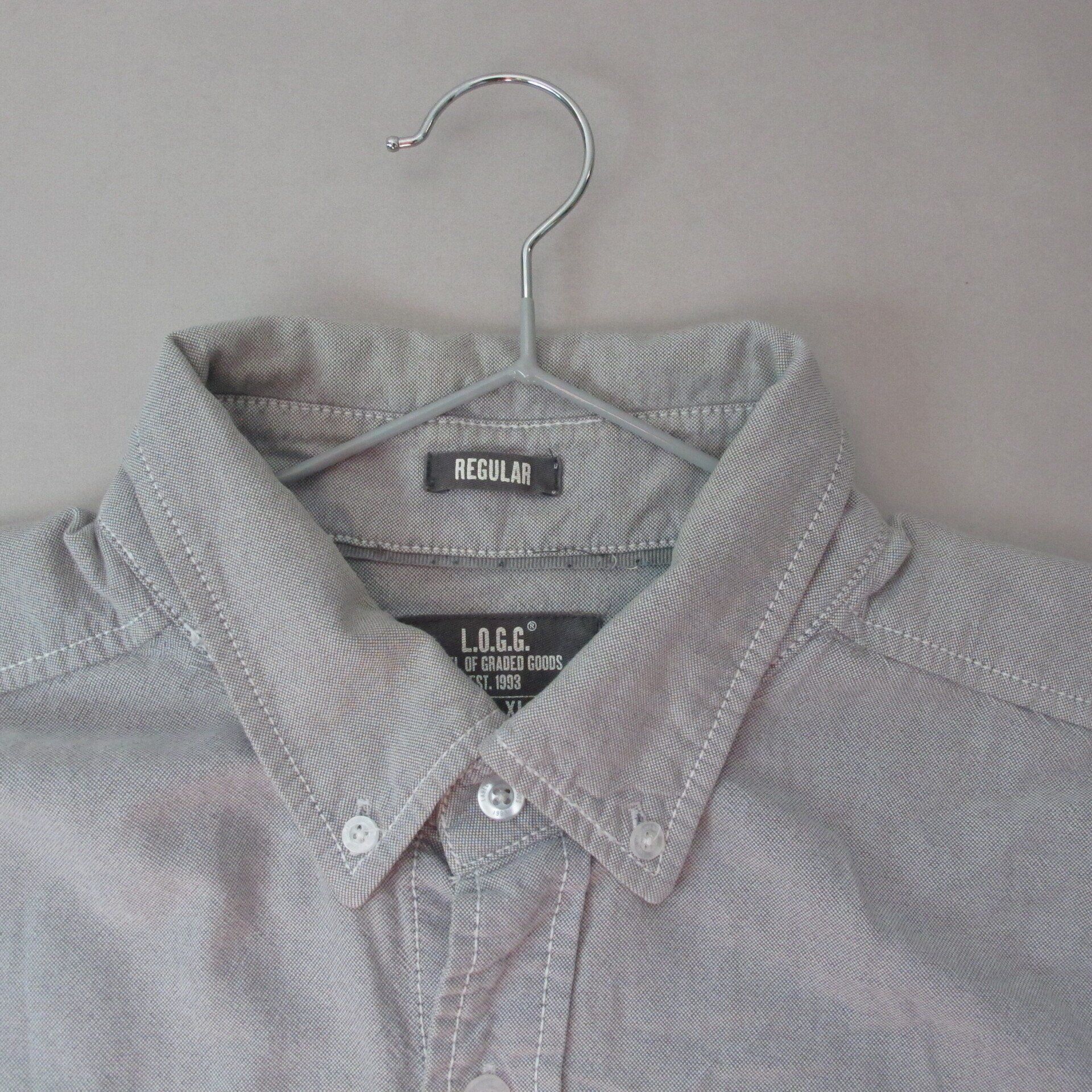 Een grijs shirt hangt aan een metalen hanger