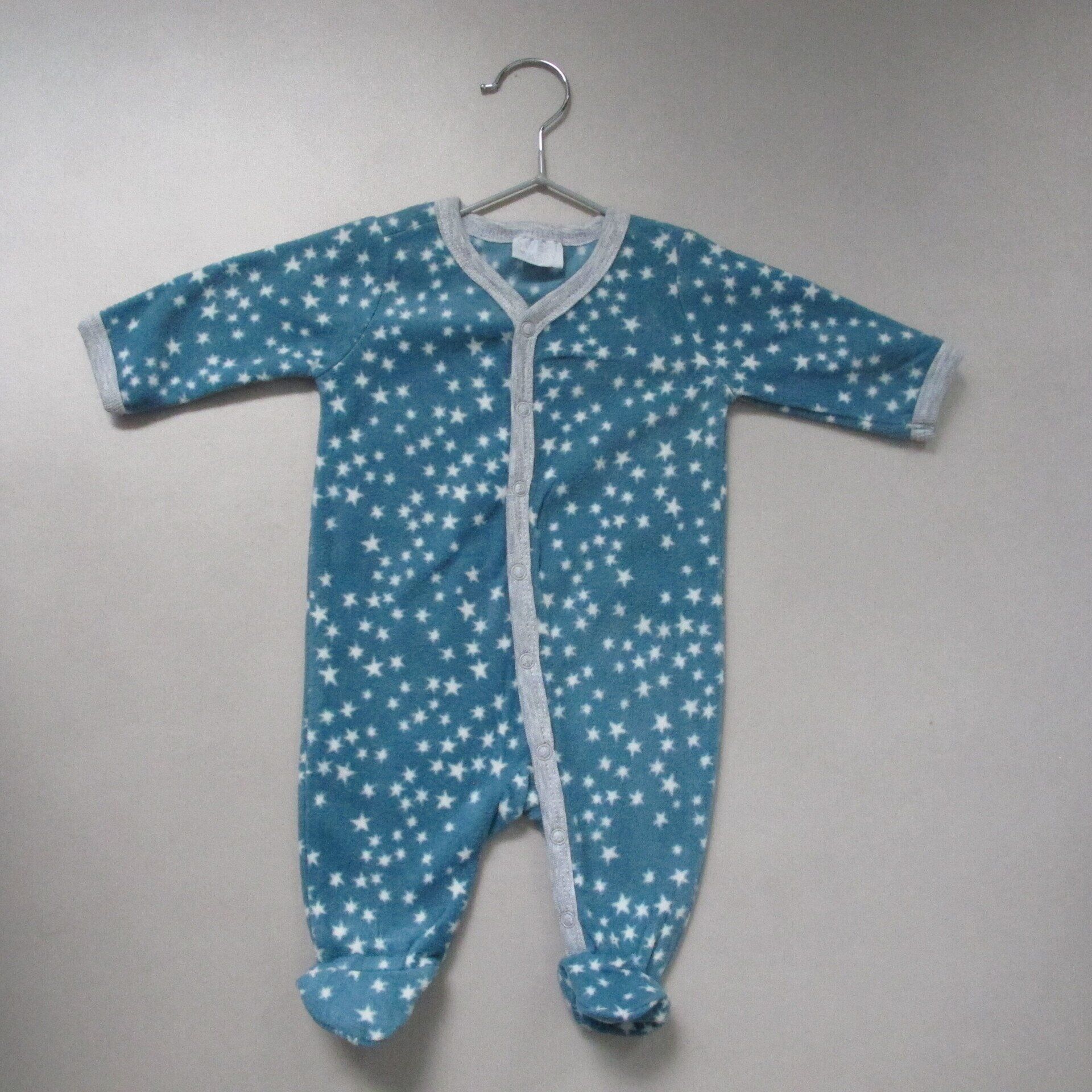 Een blauw baby rompertje met witte sterren erop hangt aan een hanger