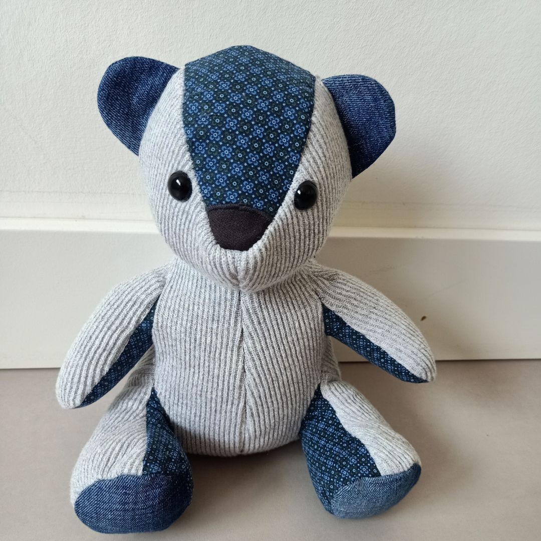 Een grijs en blauwe herinneringsbeer zit op een tafel