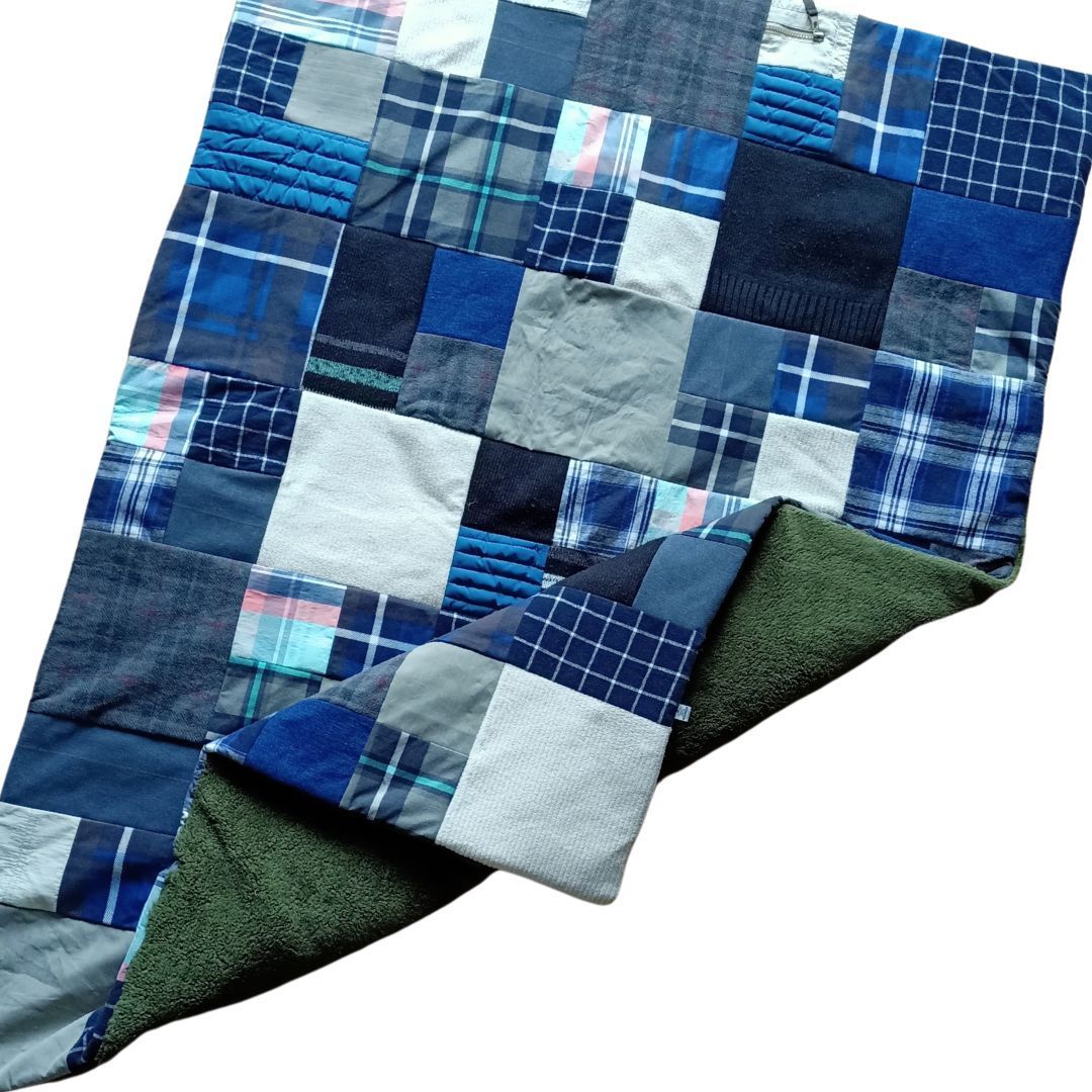 Een blauwe en grijze patchworkdeken met een groene voering