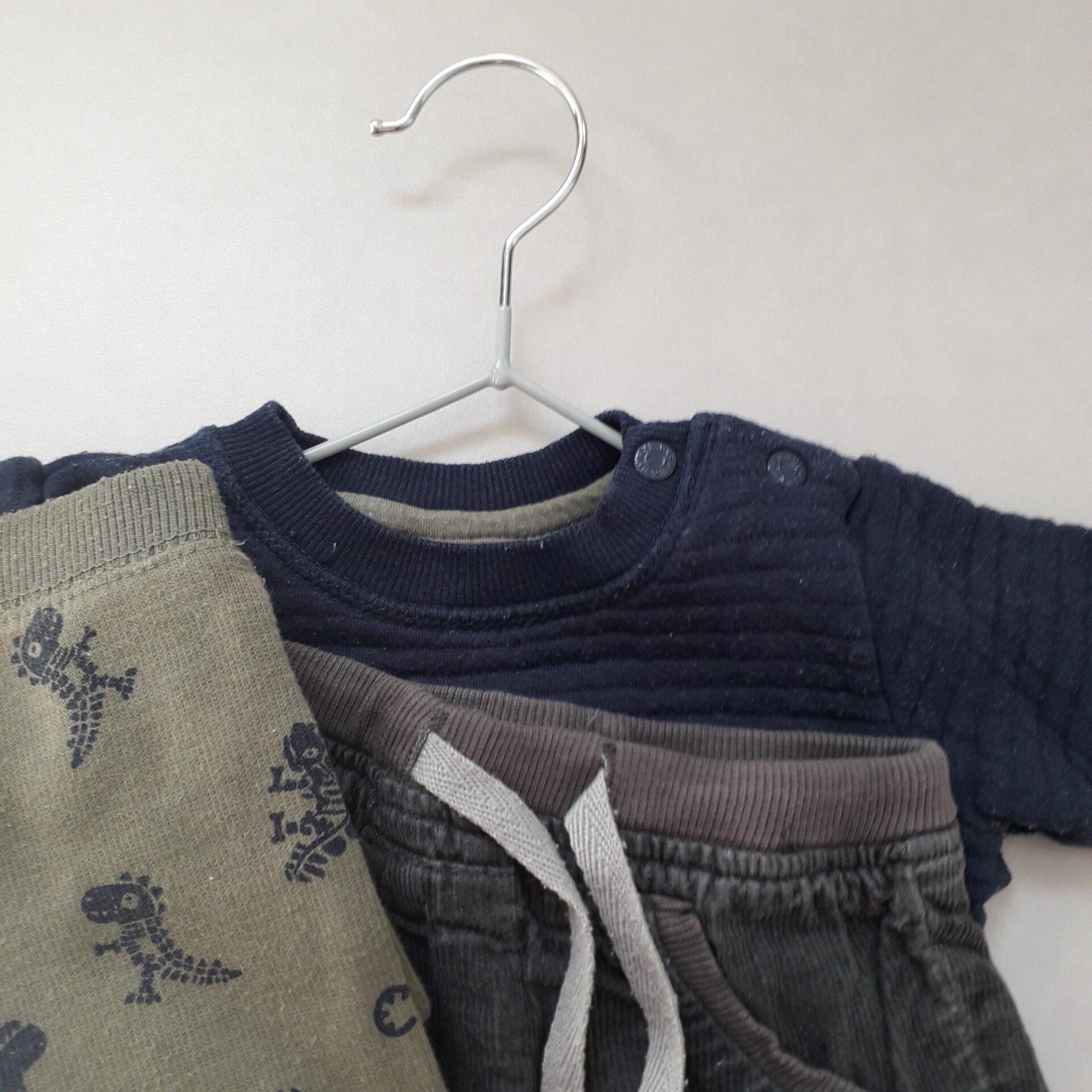 De kleertjes van een baby hangen aan een metalen hanger