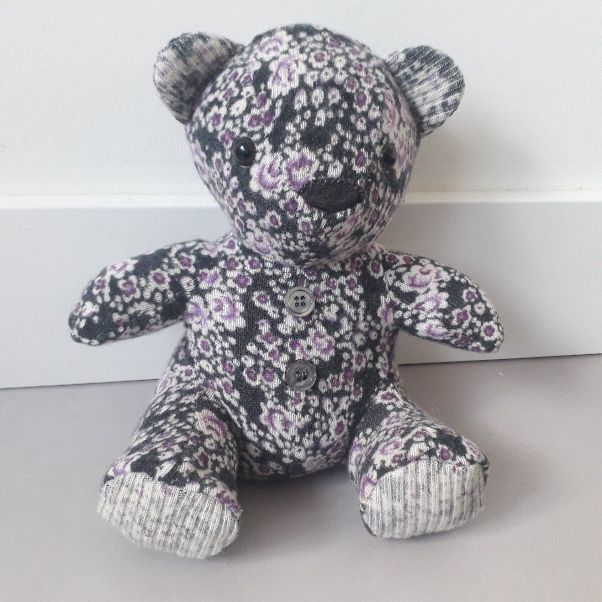 Een zwart-witte  troostbeer met paarse bloemen erop