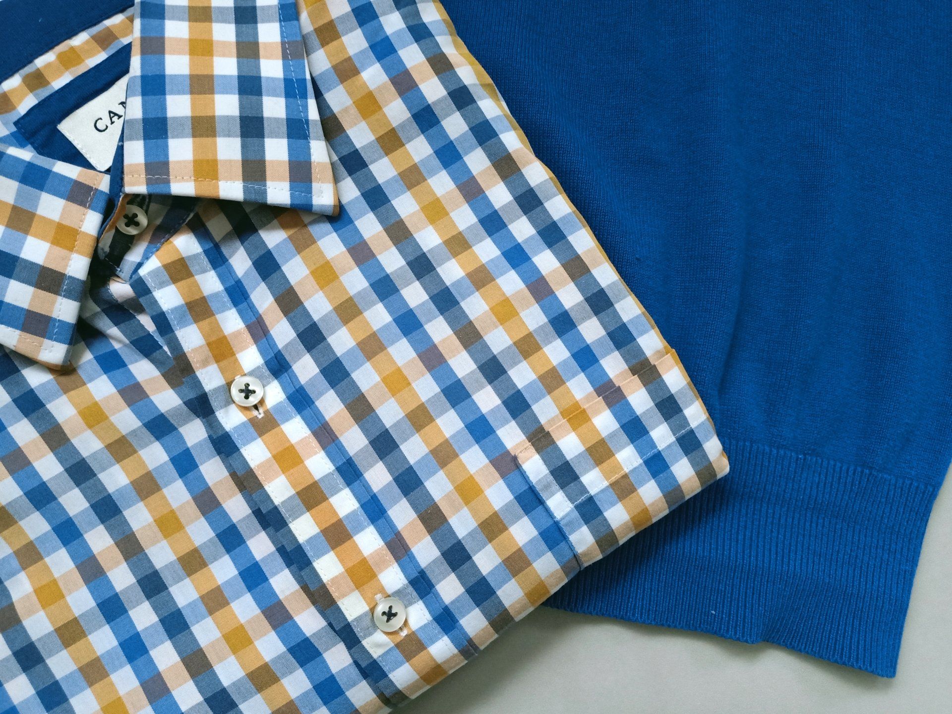 Een geruit overhemd ligt op een blauwe trui