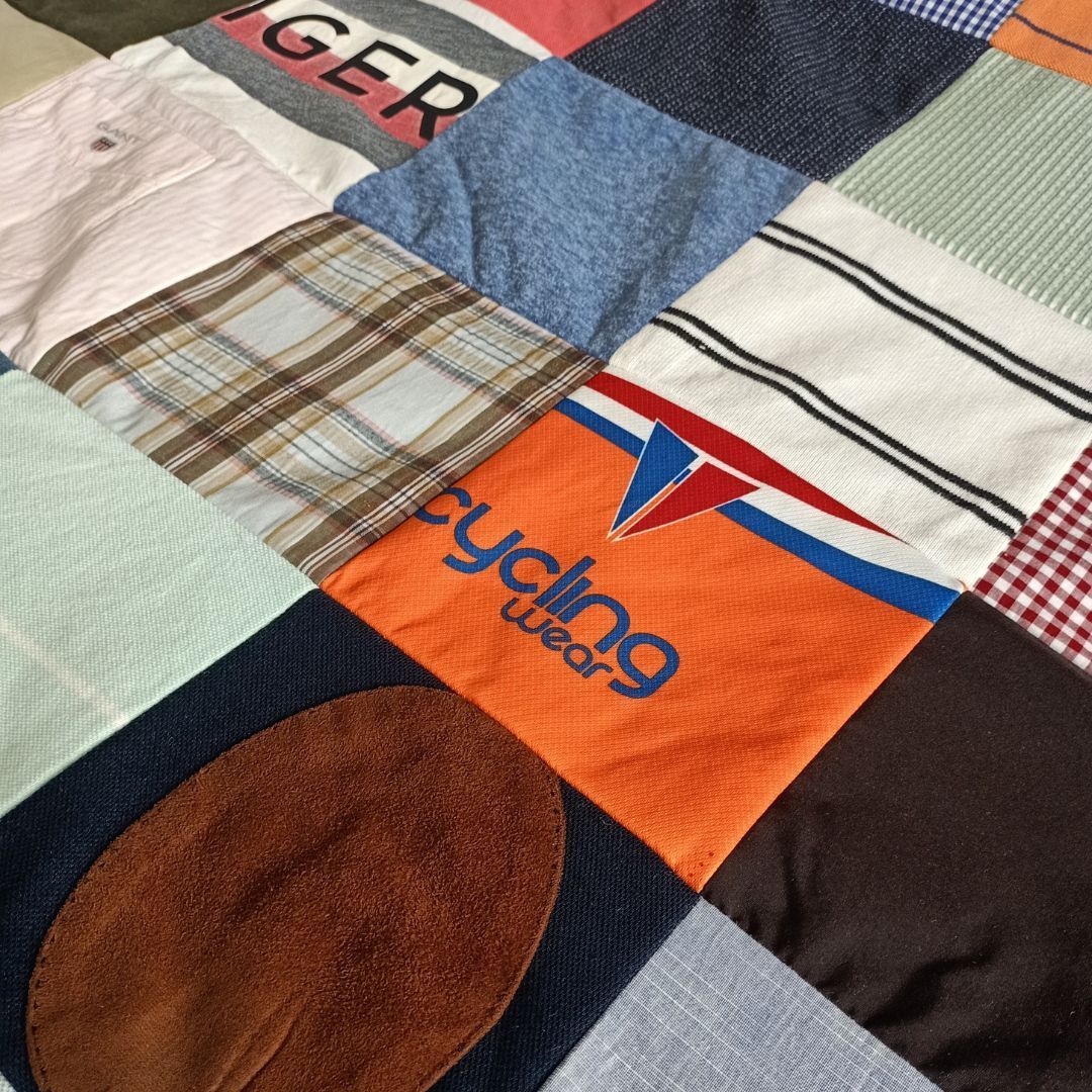 Een quilt gemaakt van oude shirts, waaronder een met de tekst wielerkleding