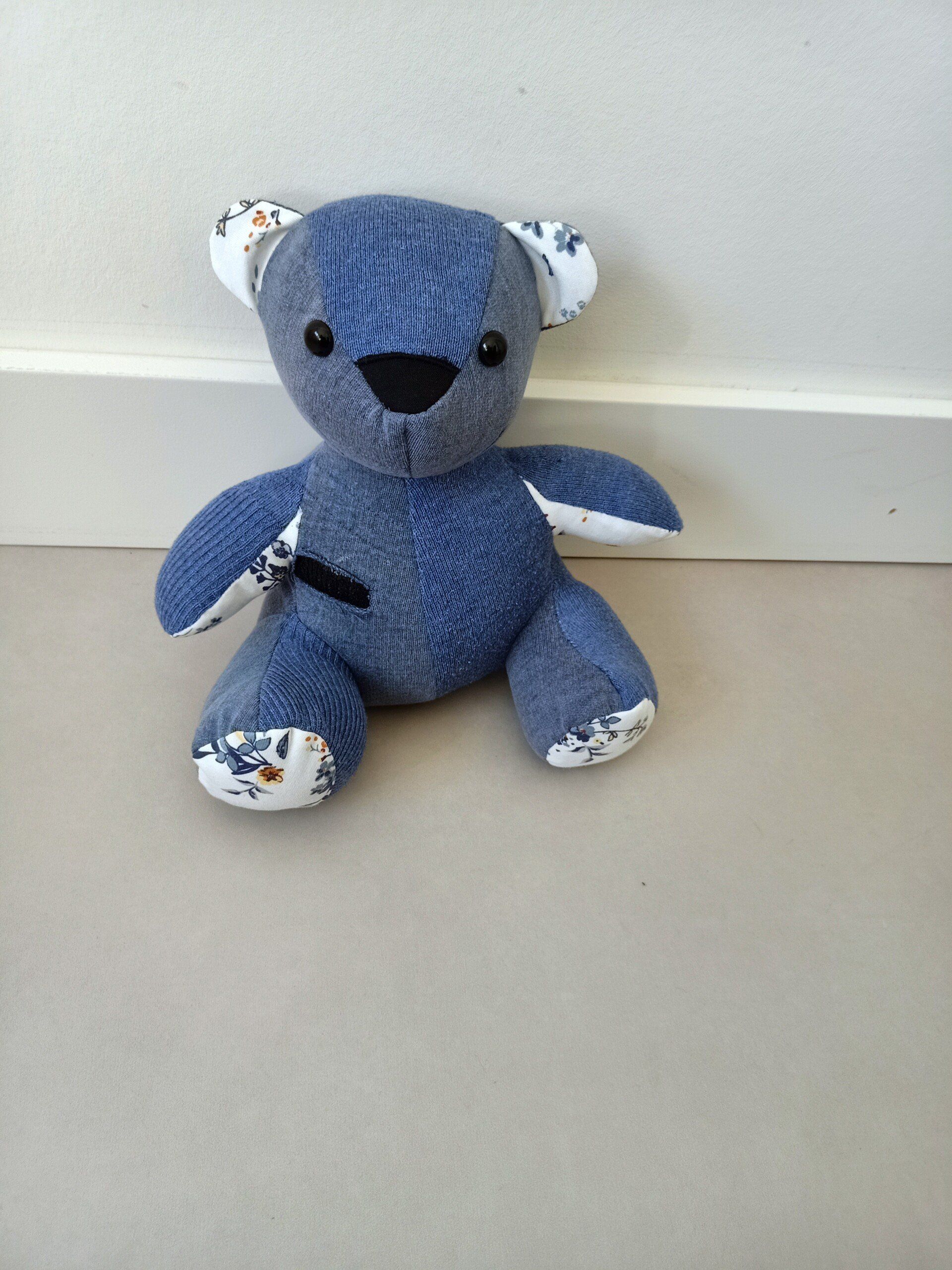 Een blauwe troostbeer zit op een wit oppervlak