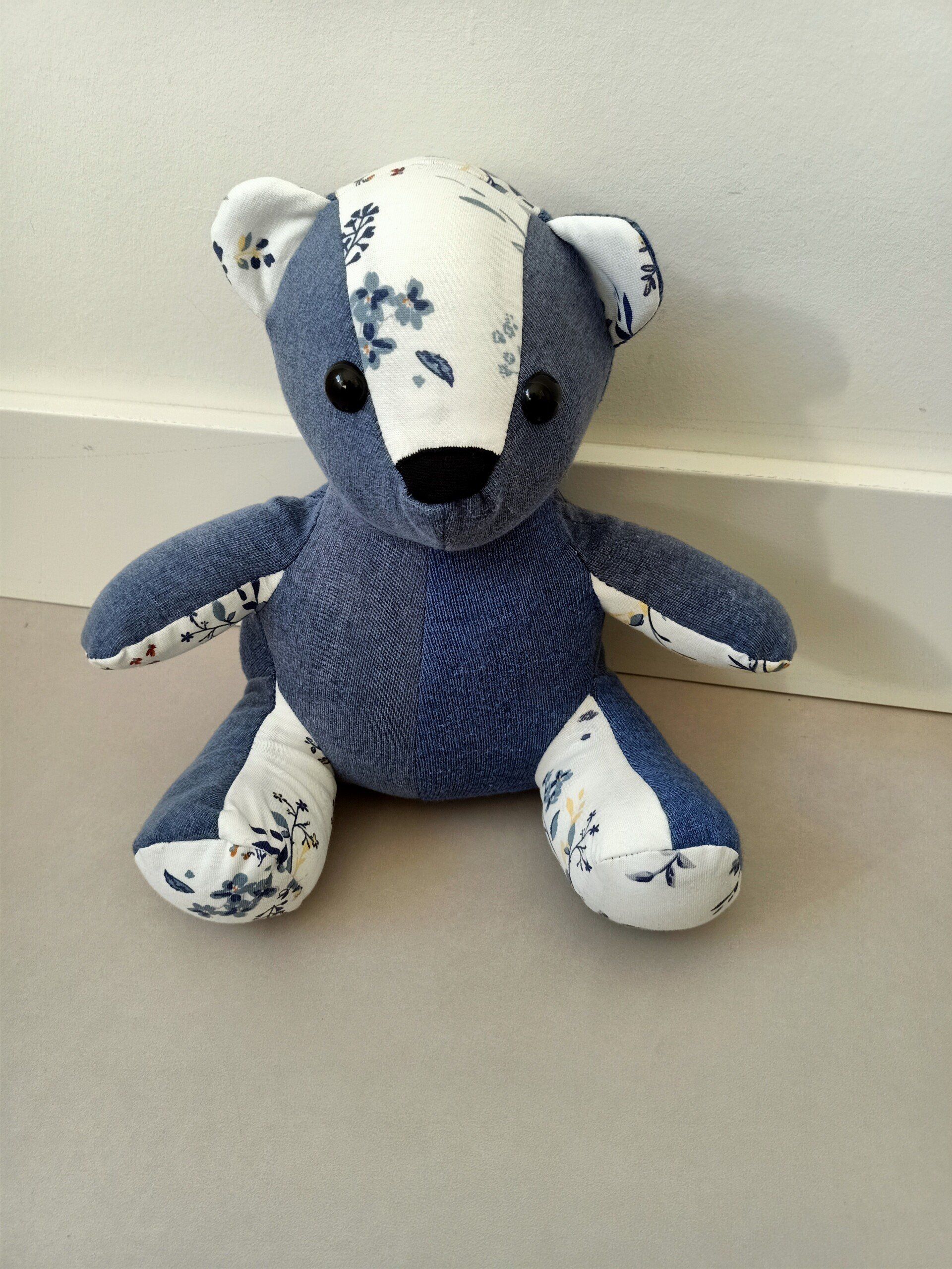 Een blauw-witte troostbeer zit op de grond