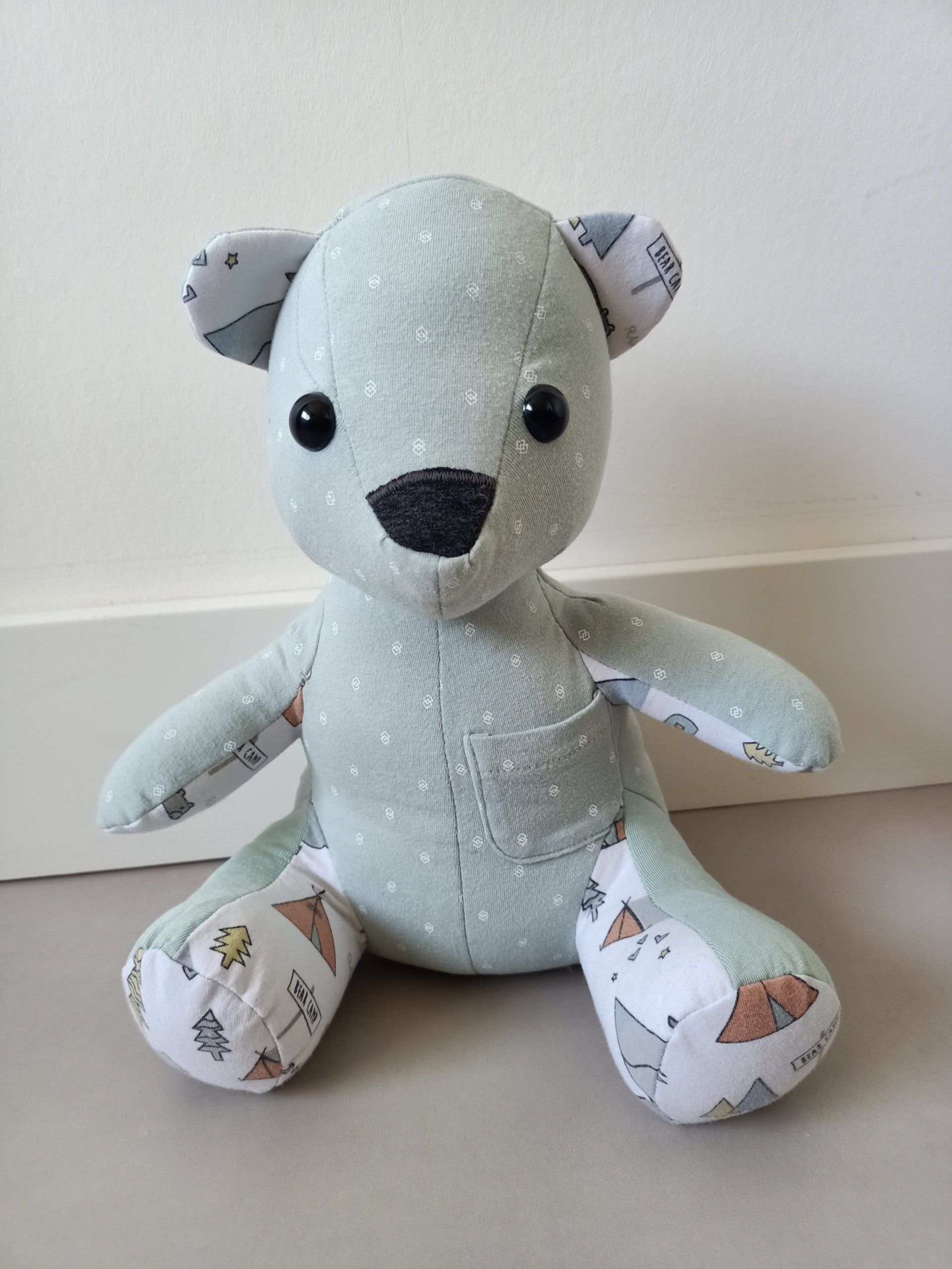 Een herinneringsbeer zit op een tafel naast een muur.