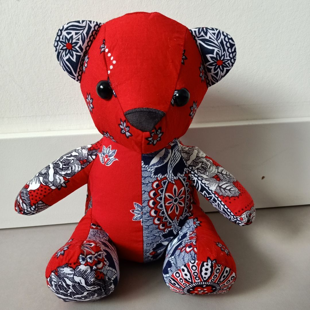 Een rode herinneringsbeer zit op een wit oppervlak