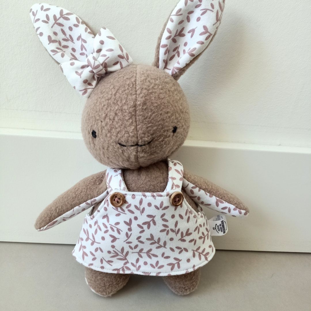 Een herinneringshaasje in een witte jurk van eerste babykleding