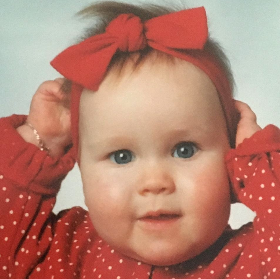 Een baby met een rode strik op haar hoofd