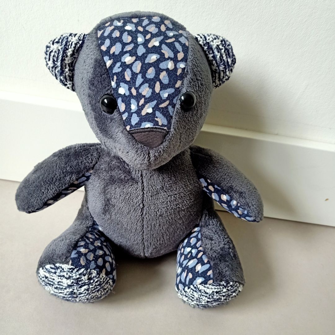 Een grijze troostbeer met blauwe vlekken op zijn gezicht