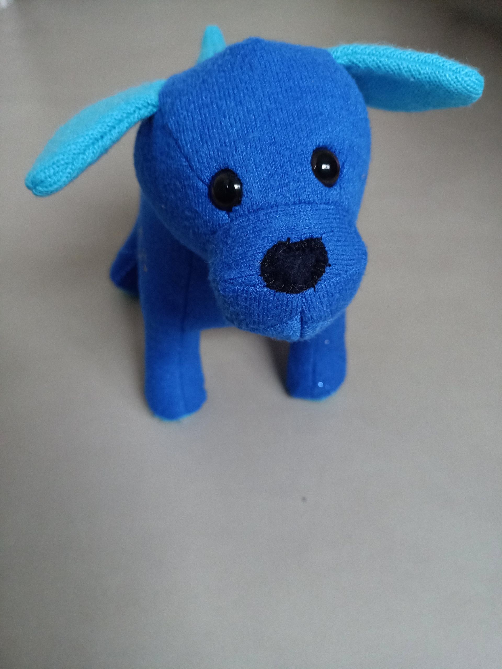Een blauwe herinneringshond met blauwe oren zit op een tafel.
