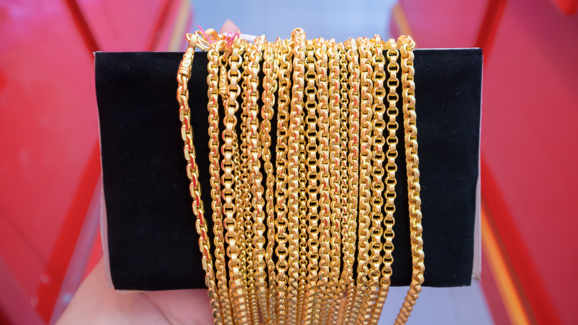 A person is holding a bunch of gold chains in their hand