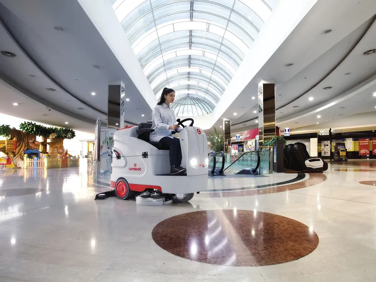 Woman driving floor cleaning machine in a shopping mall.