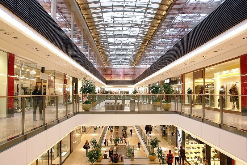 Interior of a multi-level shopping mall with stores and people.