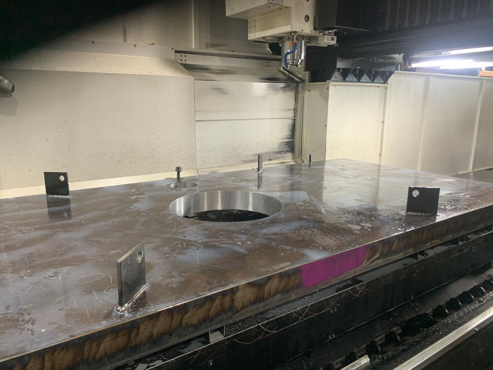A machine is cutting a piece of metal with liquid coming out of it.