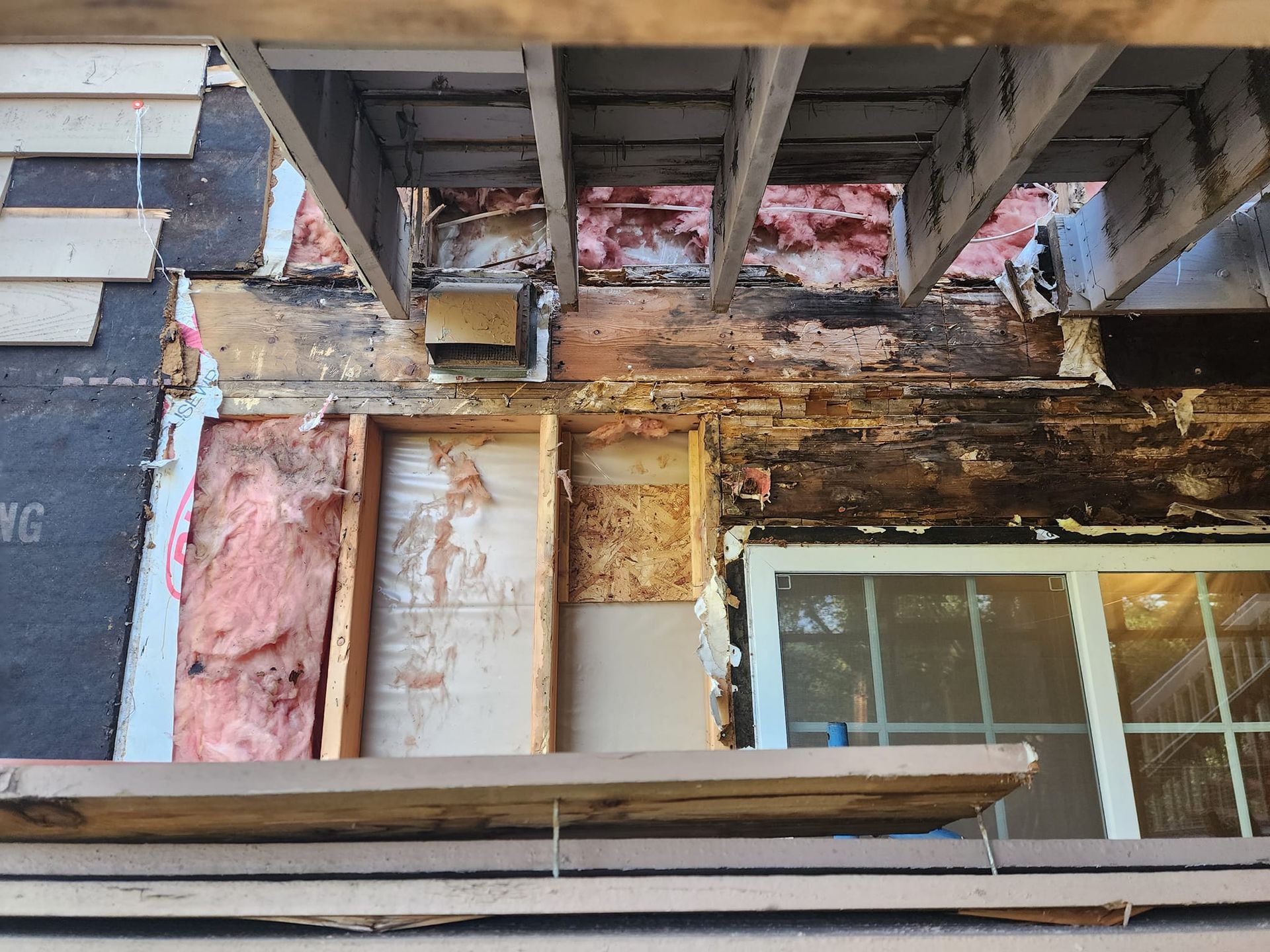 Exterior wall damage; exposed wood, insulation, and window.