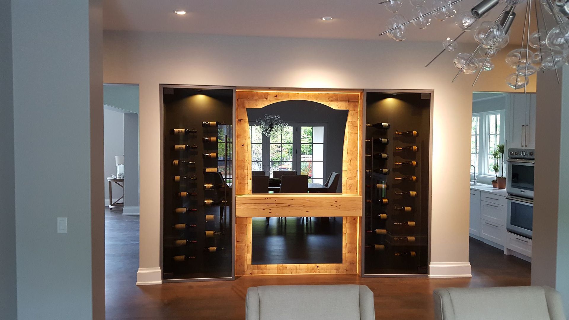 Wine storage unit with mirror and shelves, in a dining room. Dark shelves, wooden frame, and dark background.
