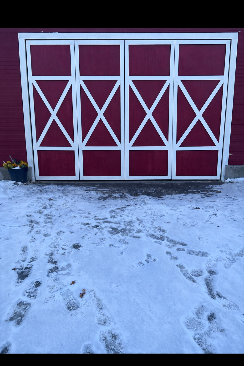 Red barn doors with white trim and snow-covered ground.