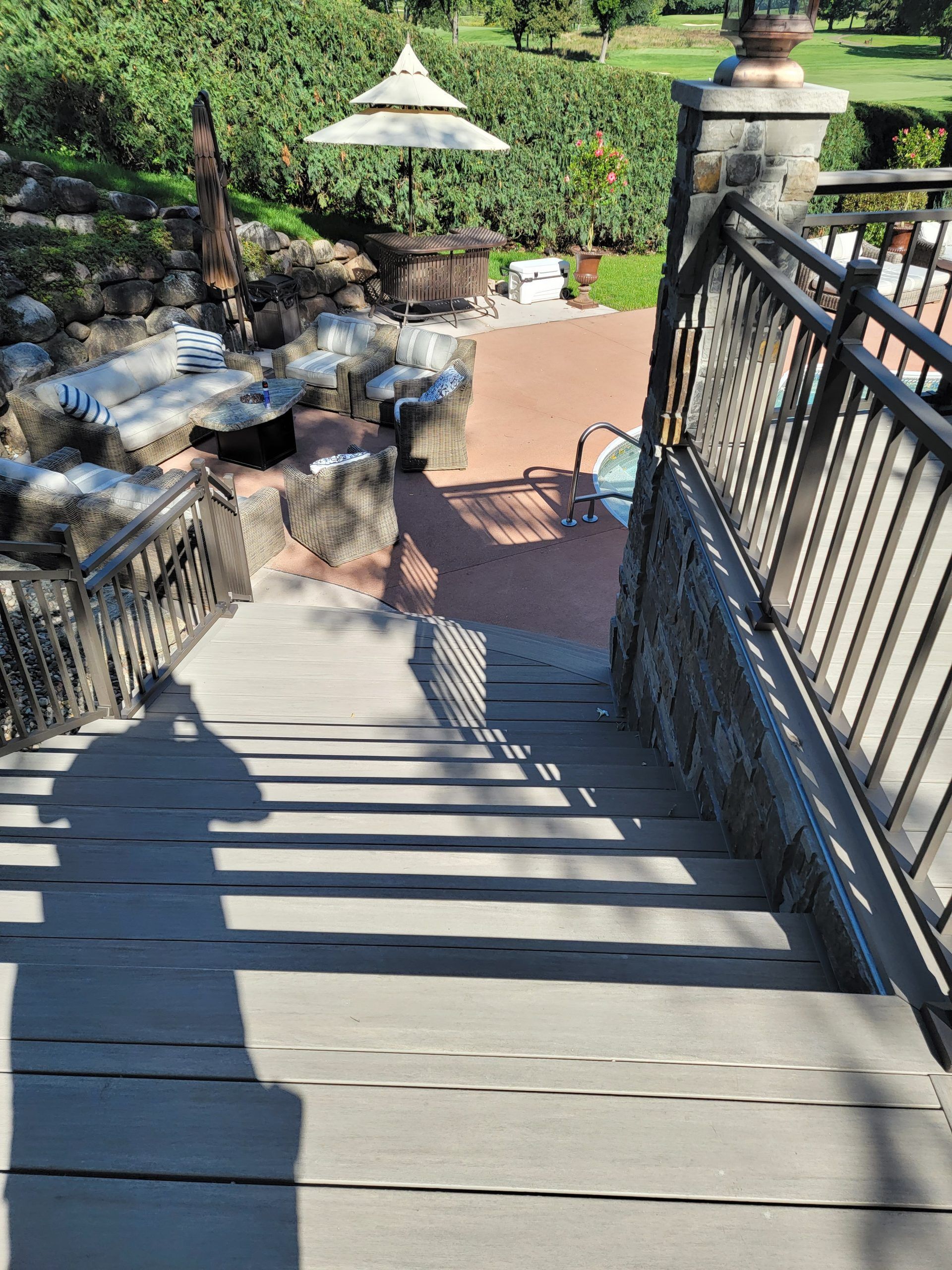 Staircase leading down, with shadow of a person. Railings on either side. Patio and gazebo in background.