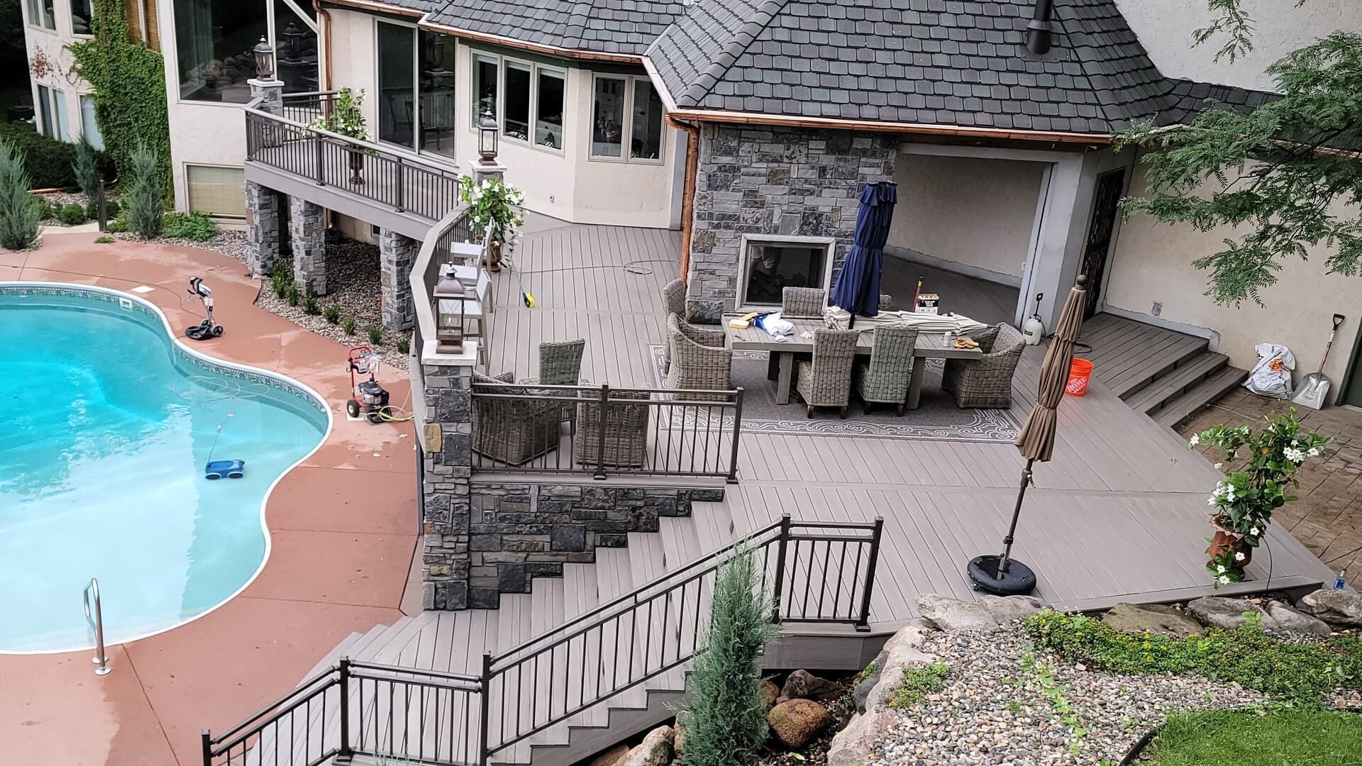 Backyard with pool, patio, and stone house. Dining area under covered stone structure.