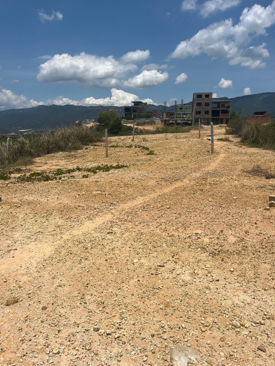 Un camino de tierra que conduce a un edificio con montañas al fondo.