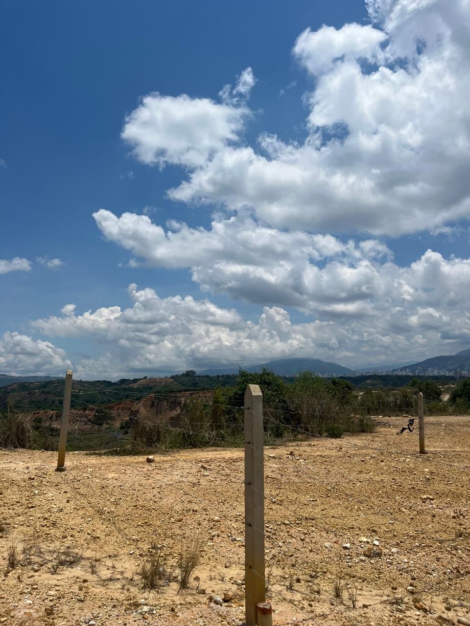 Un campo con una valla y un cielo azul con nubes