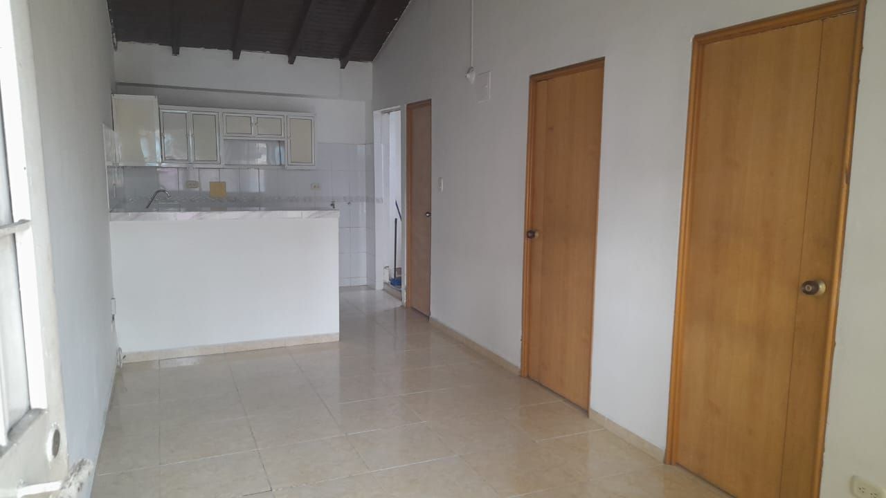 Una habitación vacía con una cocina al fondo y dos puertas.