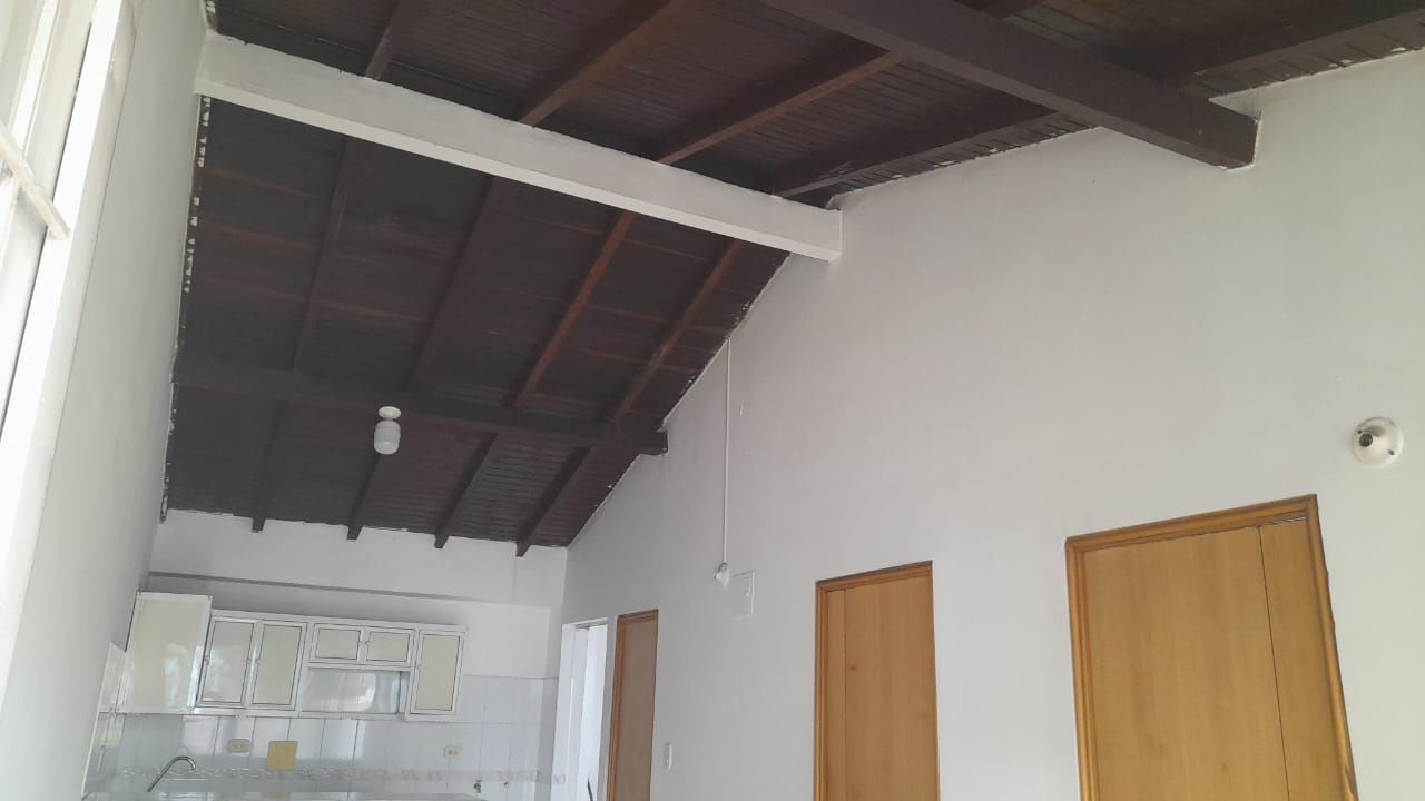 Una habitación con techo de madera y paredes blancas.