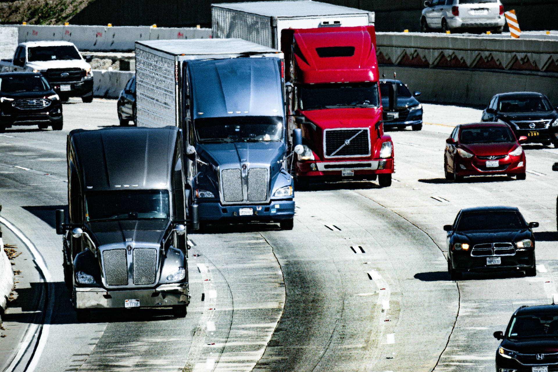 Traffic jam on a highway with trucks and cars. Blue, red, and black semi-trucks in the center.