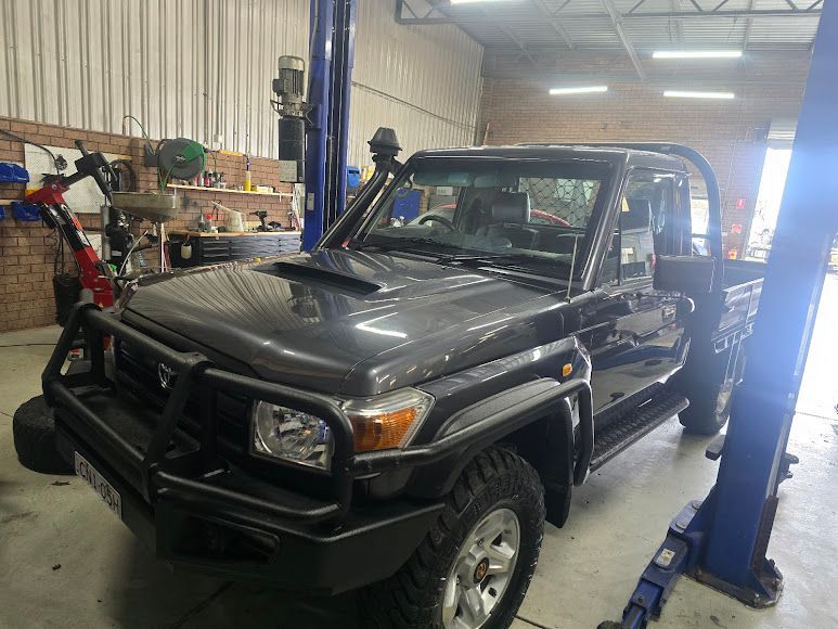 A Black Truck Is Parked On A Lift In A Garage — Nuron Inspection & Service Centre In Broadmeadow, NSW