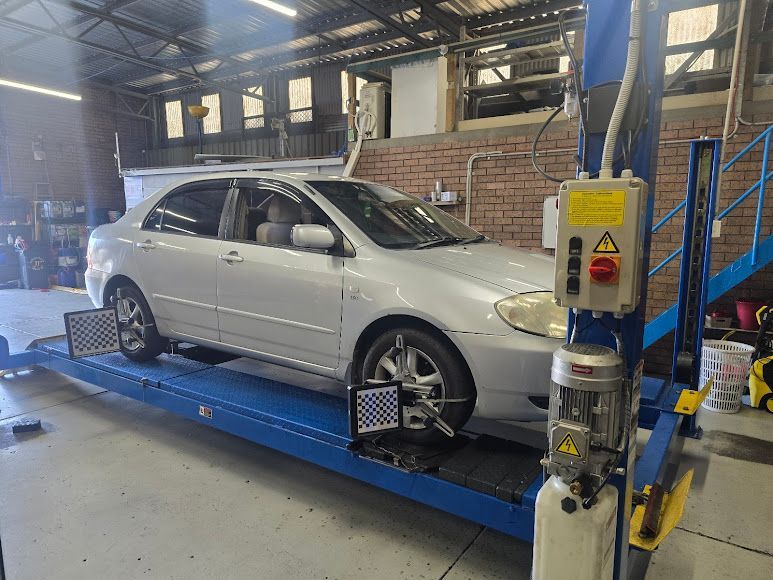 A Silver Car Is Sitting On Top Of A Blue Lift In A Garage — Nuron Inspection & Service Centre In Broadmeadow, NSW