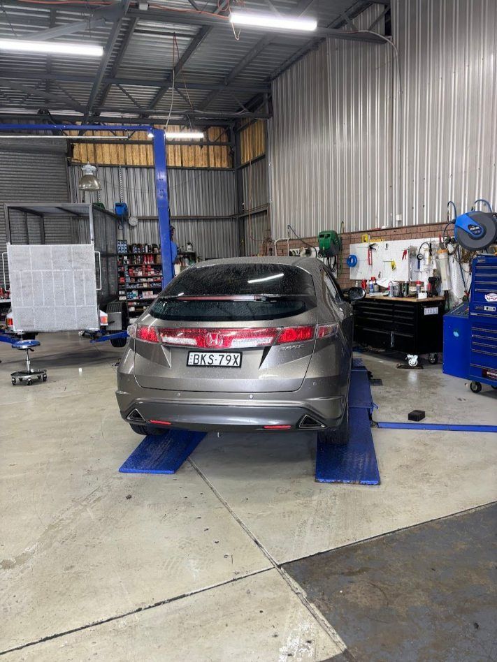A Car Is Sitting On A Lift In A Garage — Nuron Inspection & Service Centre In Broadmeadow, NSW