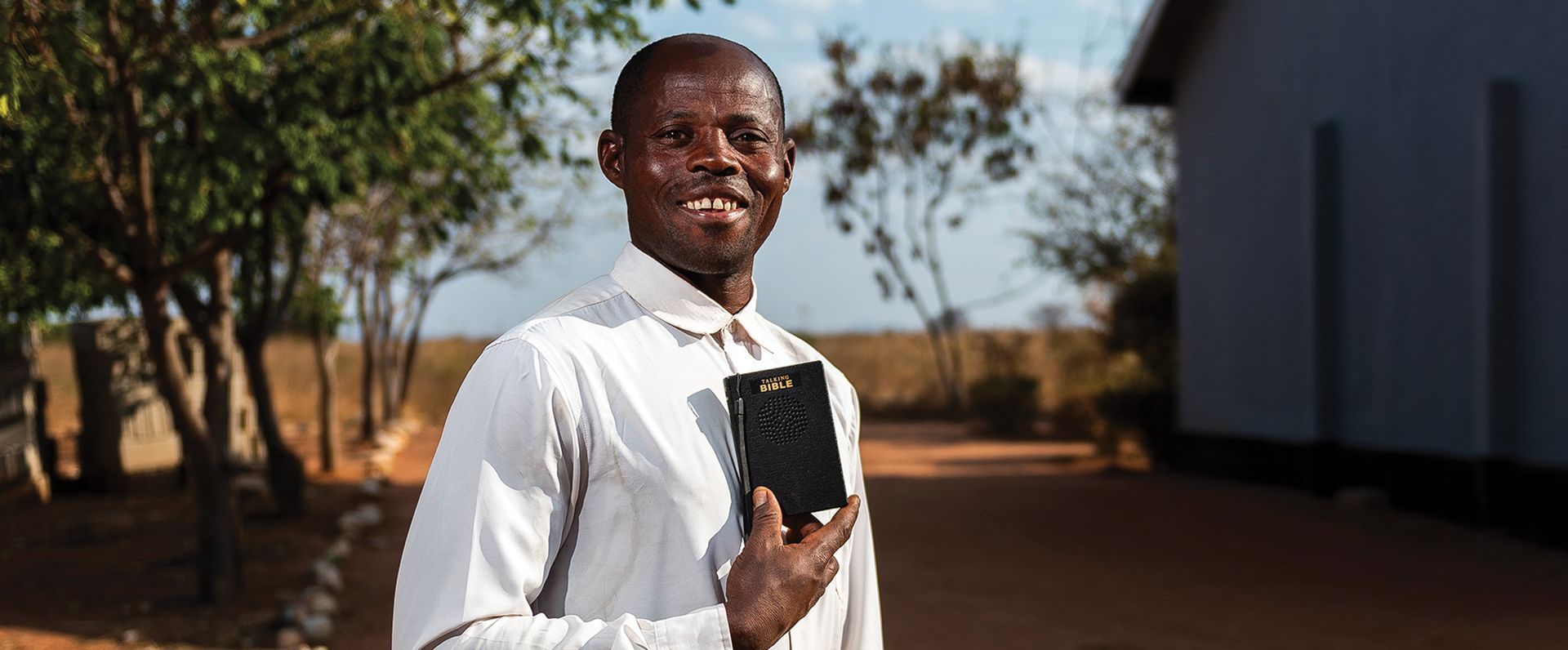 A man is holding a bible in his hand and smiling.