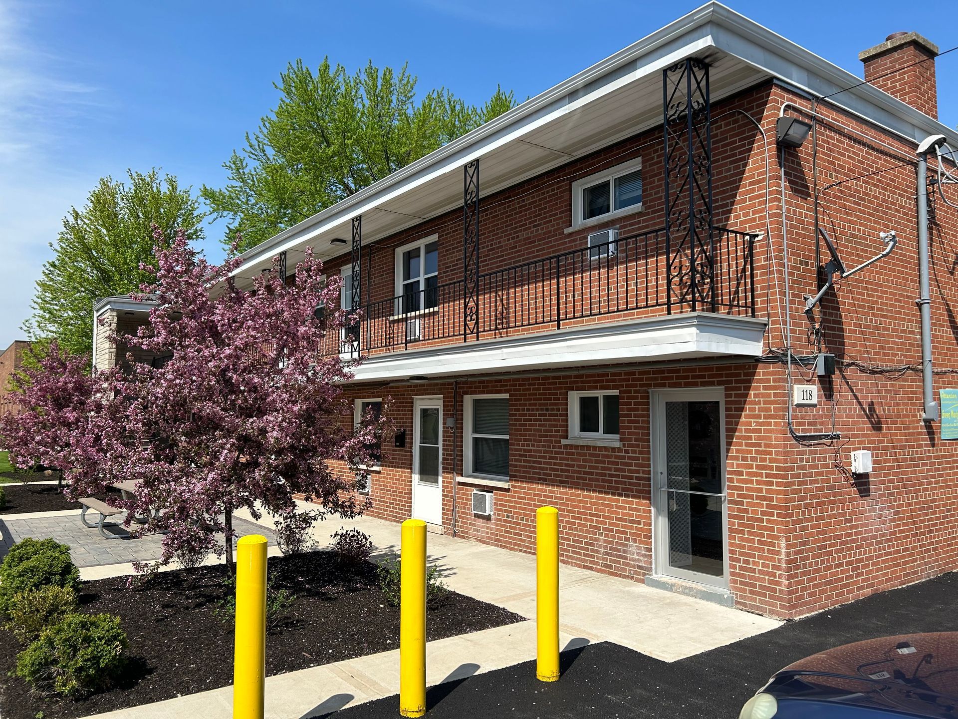 a brick building with a balcony and a tree in front of it