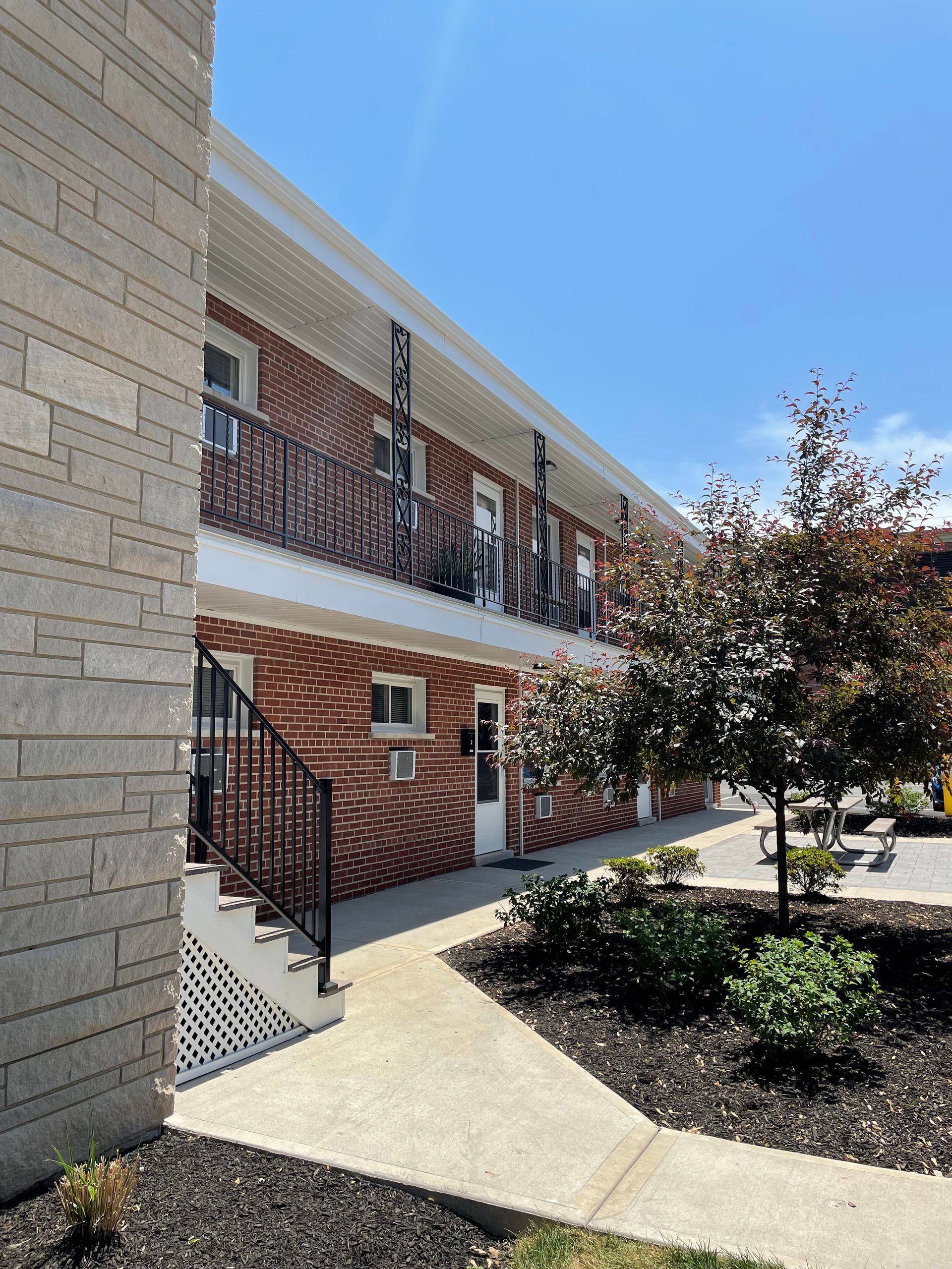 a brick apartment building with stairs and a walkway leading to it .